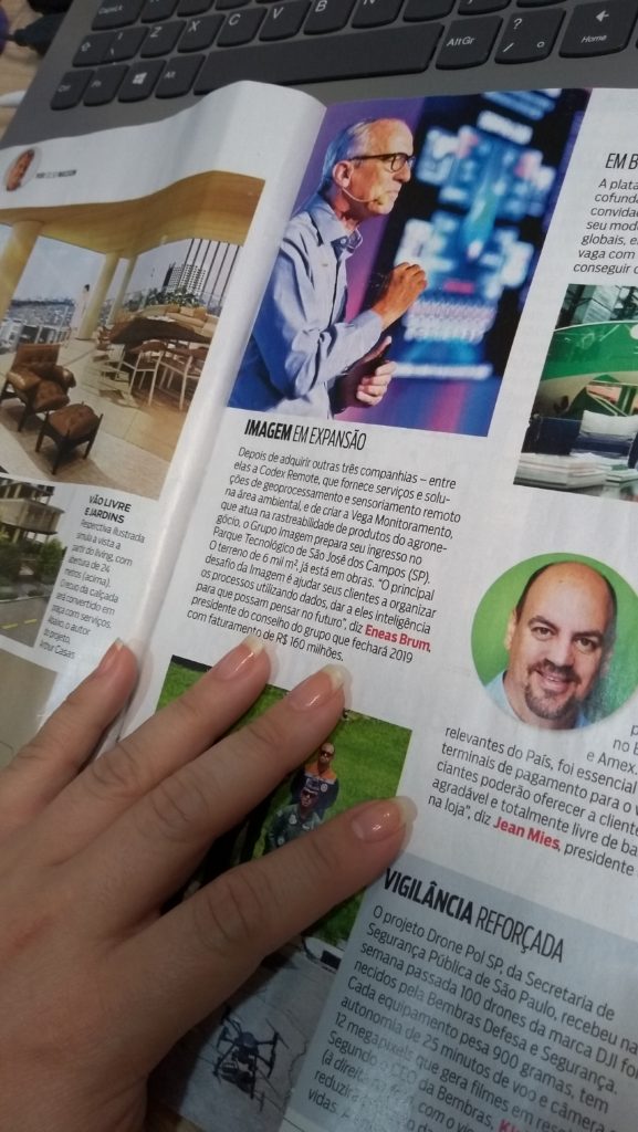 Mão feminina sobre a página da revista IstoÉ Dinheiro com reportagem "Imagem em Expansão"